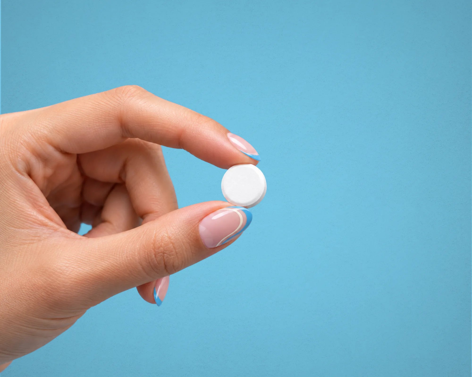 A hand holding one mint between finger and thumb.